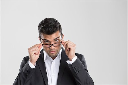 portrait young man white background - Businessman peering over glasses Stock Photo - Premium Royalty-Free, Code: 649-06353185