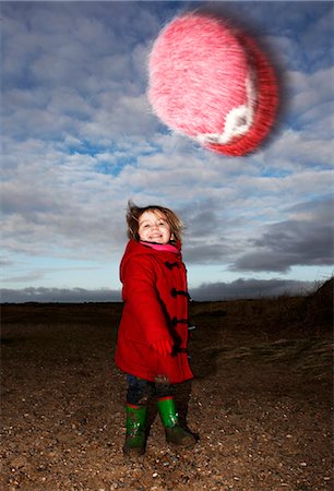 rain boots for girls - Girl playing with fuzzy hat outdoors Stock Photo - Premium Royalty-Free, Code: 649-06353208