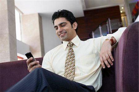 Businessman using cell phone on sofa Stock Photo - Premium Royalty-Free, Code: 649-06353399