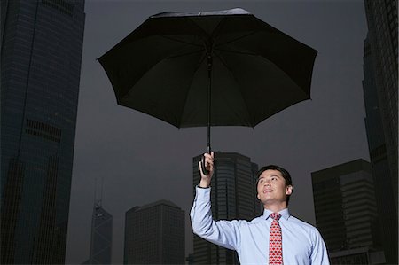Businessman with umbrella on city street Stock Photo - Premium Royalty-Free, Code: 649-06353471