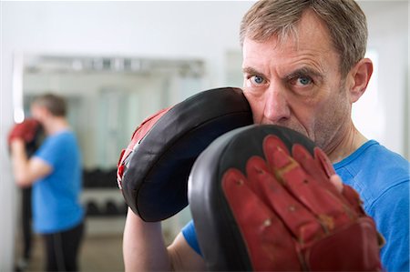 simsearch:614-06624313,k - Trainer wearing padded gloves in gym Stock Photo - Premium Royalty-Free, Code: 649-06400805