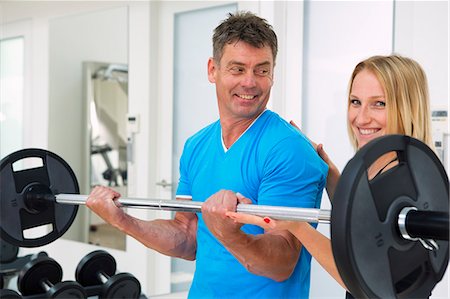 Trainer adjusting man's form in gym Foto de stock - Sin royalties Premium, Código: 649-06400822