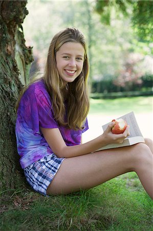 Girl eating apple and reading in park Stock Photo - Premium Royalty-Free, Code: 649-06400854