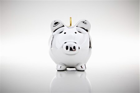 Gold coin dropping into piggy bank Stock Photo - Premium Royalty-Free, Code: 649-06400877