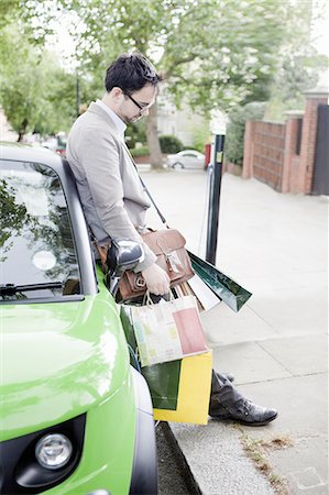 Man with shopping bags leaning on car Foto de stock - Sin royalties Premium, Código: 649-06401118