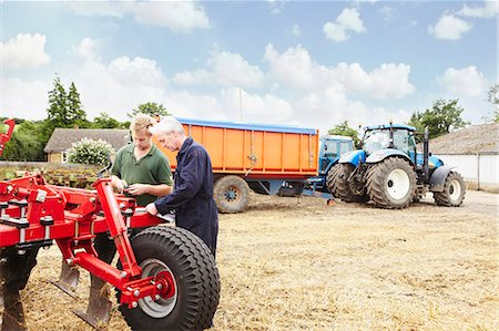 simsearch:649-06353290,k - Farmers adjusting machinery in field Fotografie stock - Premium Royalty-Free, Codice: 649-06401214