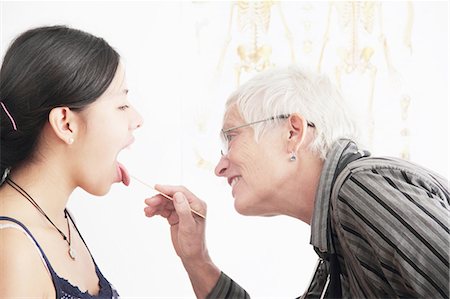 Doctor checking teenage girl's throat Stock Photo - Premium Royalty-Free, Code: 649-06401288