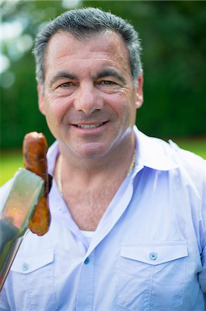 portrait man lifestyle summer closeup - Smiling man grilling hot dog outdoors Stock Photo - Premium Royalty-Free, Code: 649-06401473