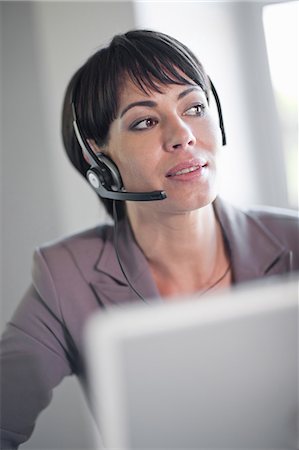 Businesswoman wearing headset at desk Foto de stock - Sin royalties Premium, Código: 649-06432279