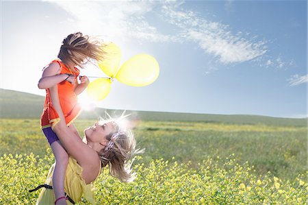 exuberant woman in sunlight - Sisters playing in field of flowers Stock Photo - Premium Royalty-Free, Code: 649-06432414