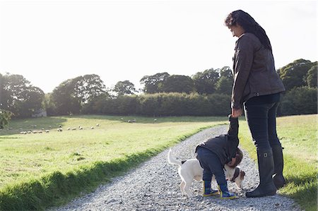 people hugging dogs - Mother and son walking dog on dirt road Stock Photo - Premium Royalty-Free, Code: 649-06432439