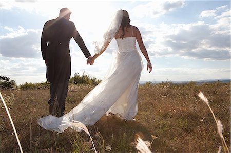 Newlywed couple holding hands in grass Foto de stock - Sin royalties Premium, Código: 649-06432566