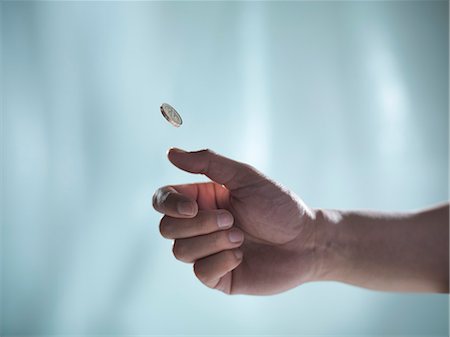 Close up of hand tossing coin Stock Photo - Premium Royalty-Free, Code: 649-06432986