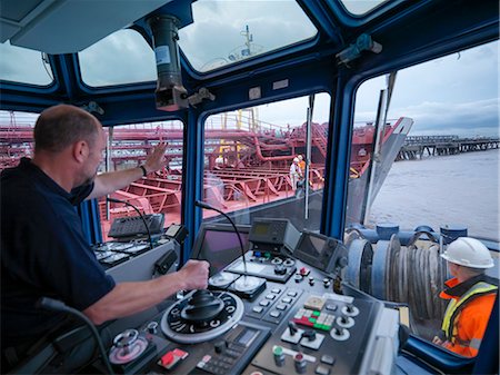 Worker driving tugboat in wheelhouse Stock Photo - Premium Royalty-Free, Code: 649-06433066