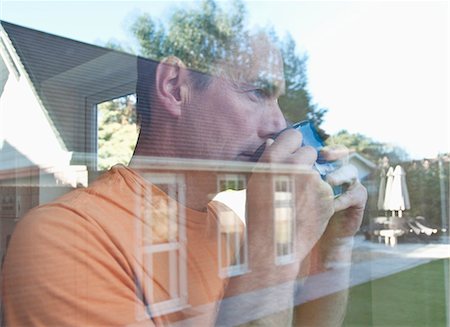 Man having coffee reflected in window Stock Photo - Premium Royalty-Free, Code: 649-06433539