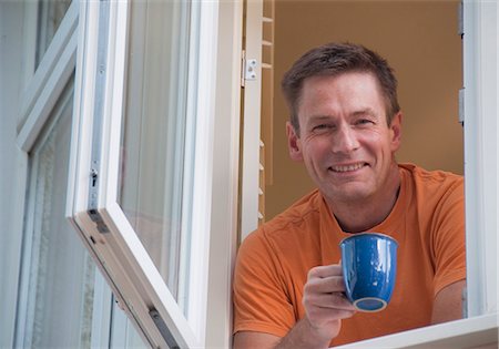 portrait man 40 years - Man with coffee leaning out window Foto de stock - Sin royalties Premium, Código: 649-06433540