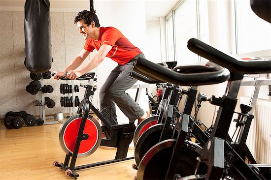 Man using stationary bicycle at gym Foto de stock - Sin royalties Premium, Código de la imagen: 649-06433569