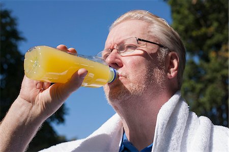 Older man drinking orange juice outdoors Stock Photo - Premium Royalty-Free, Code: 649-06433616