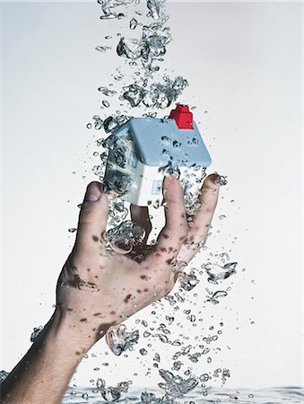 selling home - Hand grasping model house in water Stock Photo - Premium Royalty-Free, Code: 649-06433666
