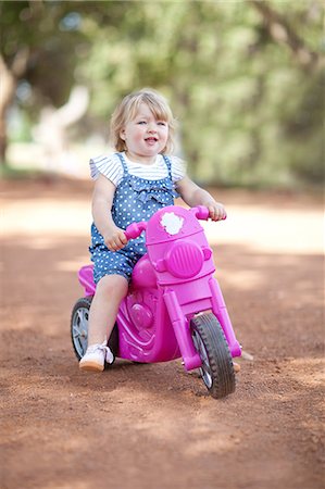 Toddler girl riding toy on dirt road Stock Photo - Premium Royalty-Free, Code: 649-06488440
