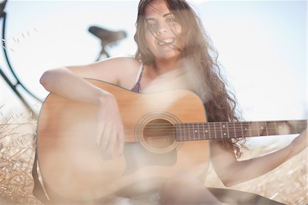 Woman playing guitar in tall grass Stock Photo - Premium Royalty-Free, Code: 649-06488529