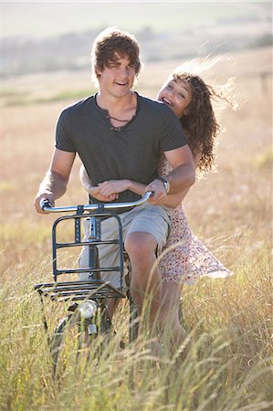 Couple riding bicycle in tall grass Stock Photo - Premium Royalty-Free, Code: 649-06488576