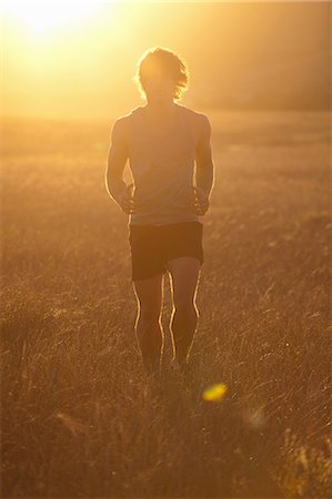 simsearch:649-06488586,k - Man running in tall grass at sunset Stock Photo - Premium Royalty-Free, Code: 649-06488585