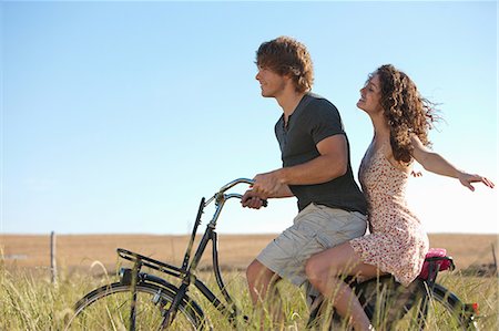pareja de jóvenes - Couple riding bicycle in tall grass Foto de stock - Sin royalties Premium, Código: 649-06488581