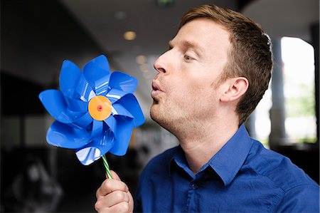 simsearch:649-06488793,k - Man blowing pinwheel indoors Stock Photo - Premium Royalty-Free, Code: 649-06488793