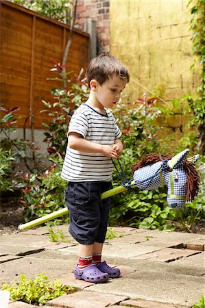 Boy playing with toy horse in garden Stock Photo - Premium Royalty-Free, Code: 649-06488920