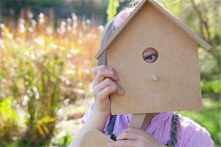 Girl peeking through birdhouse Stock Photo - Premium Royalty-Free, Code: 649-06489036