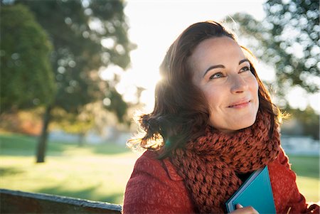daydreaming (eyes open) - Smiling woman holding book outdoors Stock Photo - Premium Royalty-Free, Code: 649-06489061