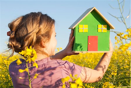 photograph of a girl dreaming - Girl holding model house in field Stock Photo - Premium Royalty-Free, Code: 649-06489088