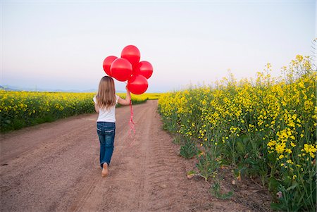 simsearch:649-06488947,k - Girl carrying balloons on dirt road Fotografie stock - Premium Royalty-Free, Codice: 649-06489102
