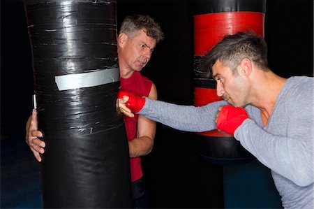 saco para socar - Boxer working with trainer in gym Foto de stock - Royalty Free Premium, Número: 649-06489198