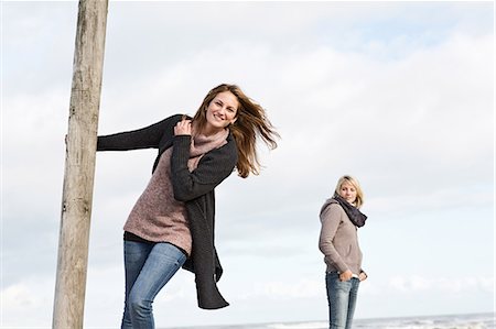 friends travel europe - Woman swinging from pole on beach Stock Photo - Premium Royalty-Free, Code: 649-06489744