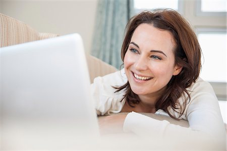 simsearch:649-06533053,k - Smiling woman using laptop on sofa Foto de stock - Royalty Free Premium, Número: 649-06533056