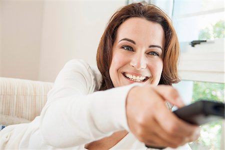 enjoying tv on couch - Smiling woman watching television Stock Photo - Premium Royalty-Free, Code: 649-06533053