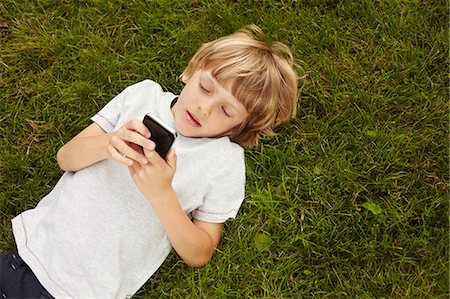 Boy using cell phone in grass Photographie de stock - Premium Libres de Droits, Code: 649-06533113