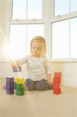 Girl playing with toy blocks on floor Foto de stock - Sin royalties Premium, Código: 649-06533142