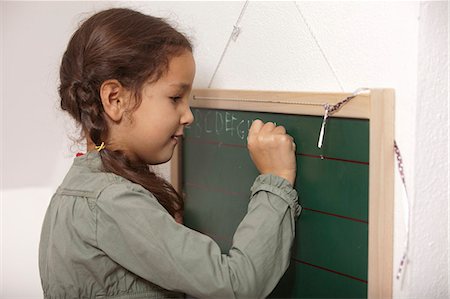 Girl writing on small chalkboard Foto de stock - Sin royalties Premium, Código: 649-06533515