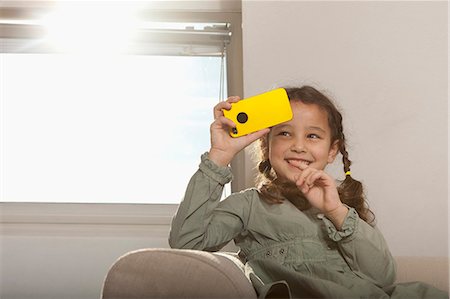 pigtails braided - Girl playing with cell phone on sofa Stock Photo - Premium Royalty-Free, Code: 649-06533537