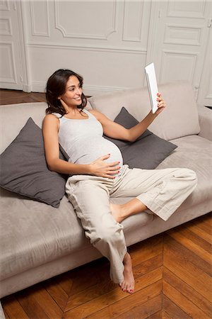 pregnant woman holding her stomach - Pregnant woman using tablet computer Foto de stock - Sin royalties Premium, Código: 649-06622048