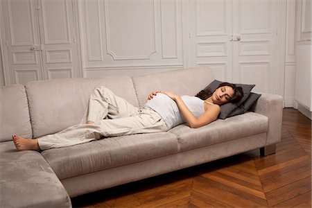 Pregnant woman holding belly on sofa Stock Photo - Premium Royalty-Free, Code: 649-06622051