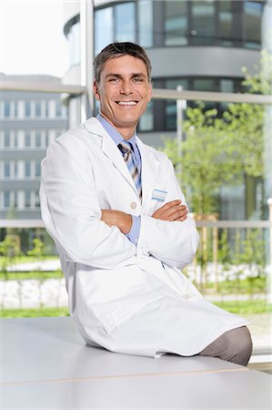 physician male - Doctor sitting on desk in office Stock Photo - Premium Royalty-Free, Code: 649-06622101