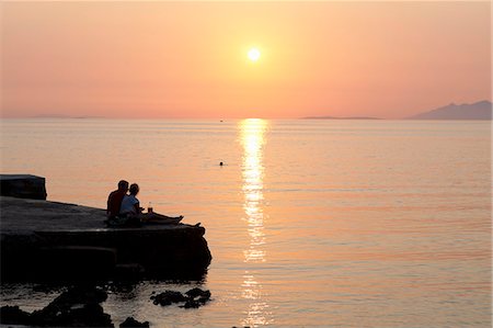 sun watch - Couple relaxing on pier at sunset Stock Photo - Premium Royalty-Free, Code: 649-06622343