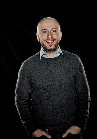 portrait black background - Smiling man with hands in pockets Stock Photo - Premium Royalty-Free, Code: 649-06622394