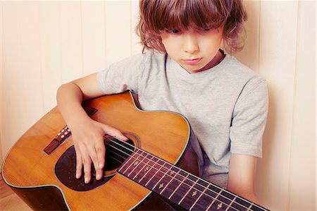 simsearch:649-06305080,k - Boy playing guitar indoors Fotografie stock - Premium Royalty-Free, Codice: 649-06622420