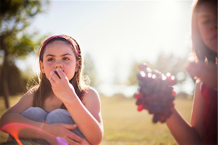 Girls eating fruit in field Stock Photo - Premium Royalty-Free, Code: 649-06622483