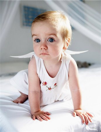 Baby girl in fairy wings crawling on bed Stock Photo - Premium Royalty-Free, Code: 649-06623020